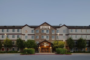 A Staybridge Suites hotel with a symmetrical facade, multiple windows, and a central entrance with a welcoming archway. - Staybridge Suites Fayetteville/Univ Of Arkansas by IHG (Fayetteville)