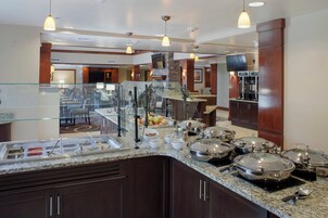 A buffet area with a variety of food options, a seating area, and a television mounted on the wall.