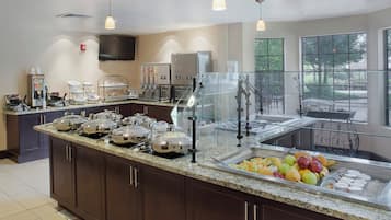 A buffet area with a variety of food options, including fruits and dairy products, and a seating area with a view outside.