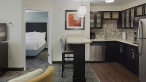 A compact hotel room with a bed, a small dining area, a kitchenette, and a bathroom. - Staybridge Suites Fayetteville/Univ Of Arkansas by IHG (Fayetteville)