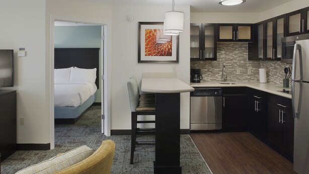 Una habitación de hotel compacta con cama, un pequeño comedor, kitchenette y baño.