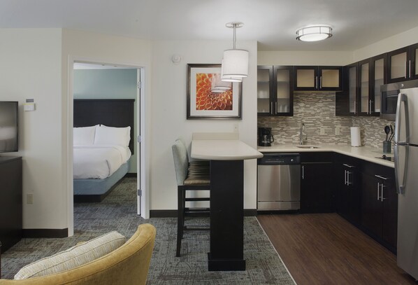 A compact hotel room with a bed, a small dining area, a kitchenette, and a bathroom. - Staybridge Suites Fayetteville/Univ Of Arkansas by IHG (Fayetteville)