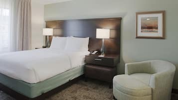 Camera d'albergo con un letto, lampade sui comodini, una sedia, un tavolino e un quadro appeso alla parete.