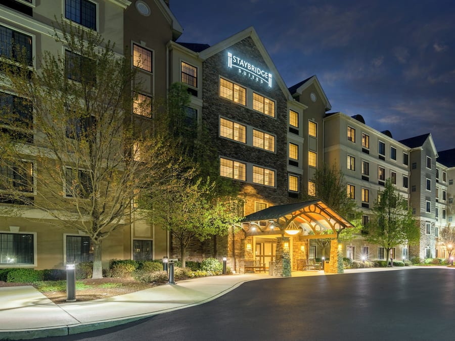 A multi-story hotel with a stone facade, a lit entrance, and a clear sky.