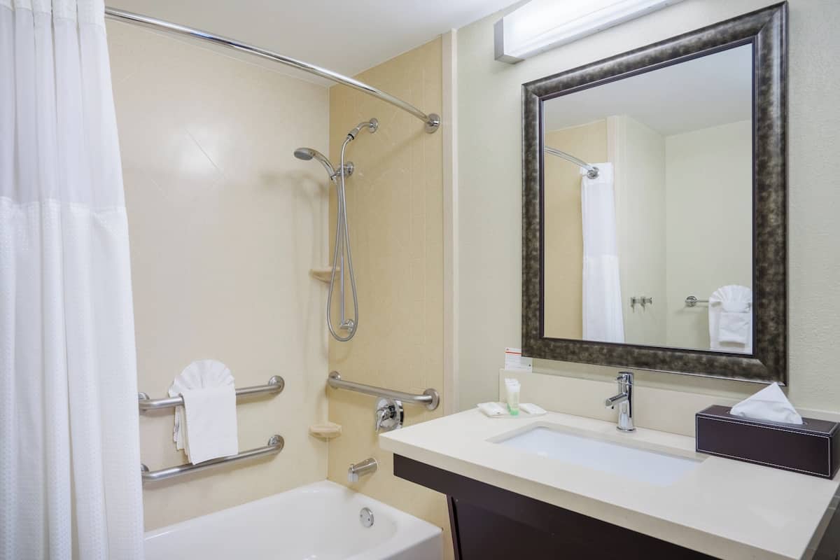 A bathroom with a bathtub, a shower, a sink, and a mirror.