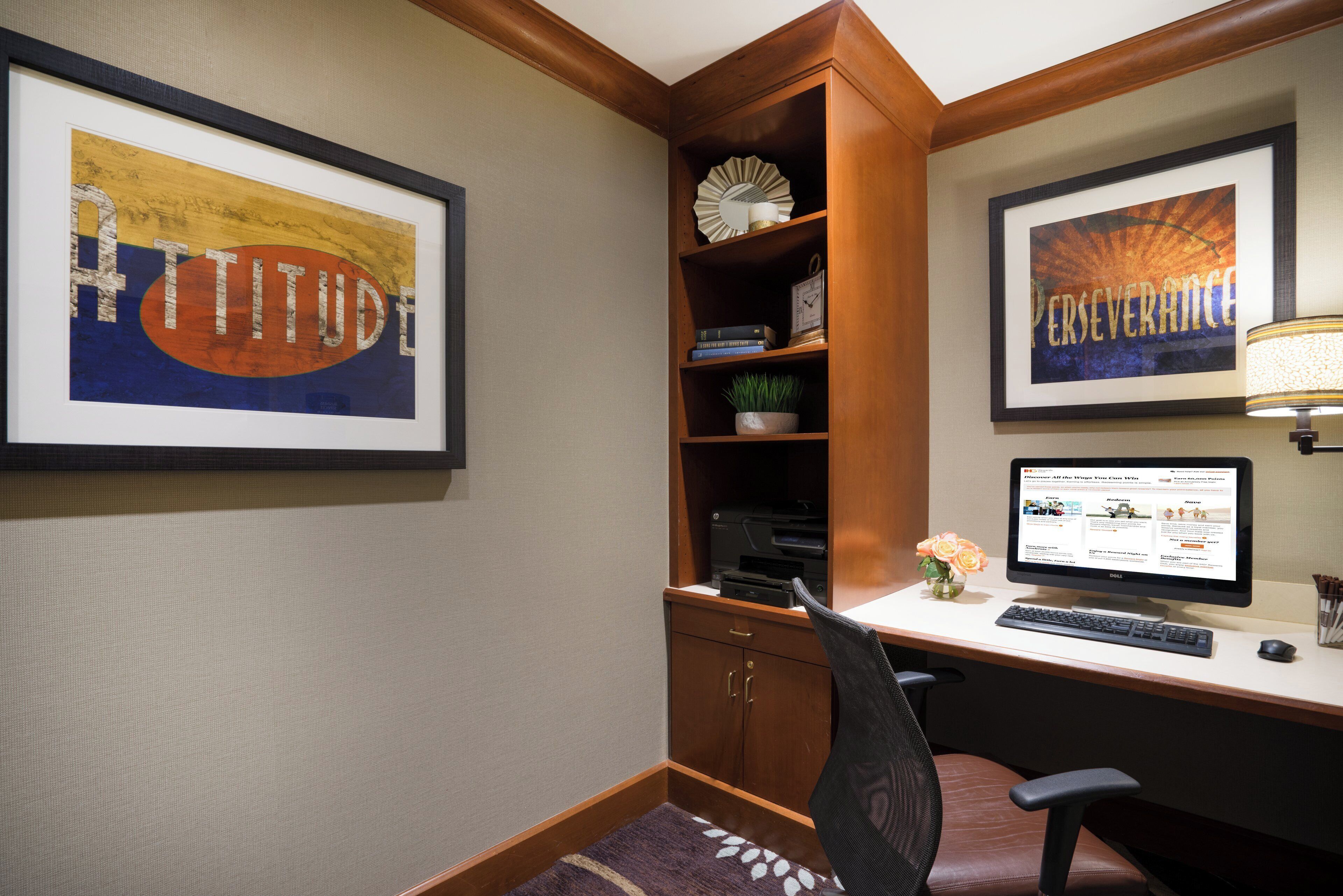 A home office with a desk, computer, and framed artwork.