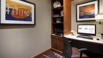 A home office with a desk, computer, and framed artwork.