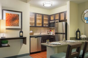 Una cocina moderna con gabinetes oscuros, electrodomésticos de acero inoxidable y una pequeña isla con asientos.
