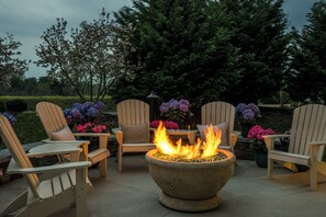 An outdoor seating area with Adirondack chairs, a fire pit, and potted plants. - Staybridge Suites Wilmington - Brandywine Valley by IHG (Glen Mills)
