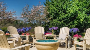 A patio area with Adirondack chairs, a large decorative bowl, and a variety of flowers.