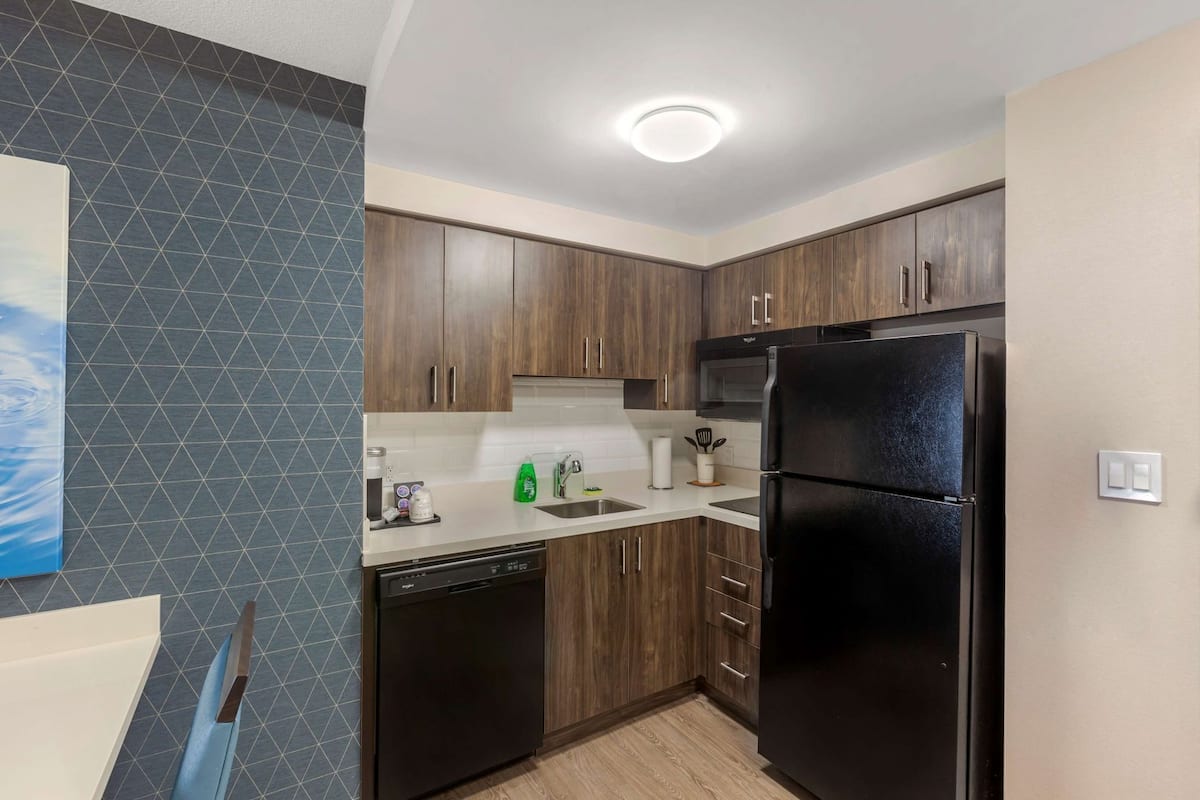 Una cocina moderna con armarios de madera, un refrigerador negro y un lavavajillas.