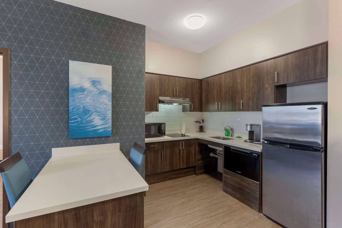 Una cocina moderna con armarios de madera oscura, electrodomésticos de acero inoxidable y encimera blanca.
