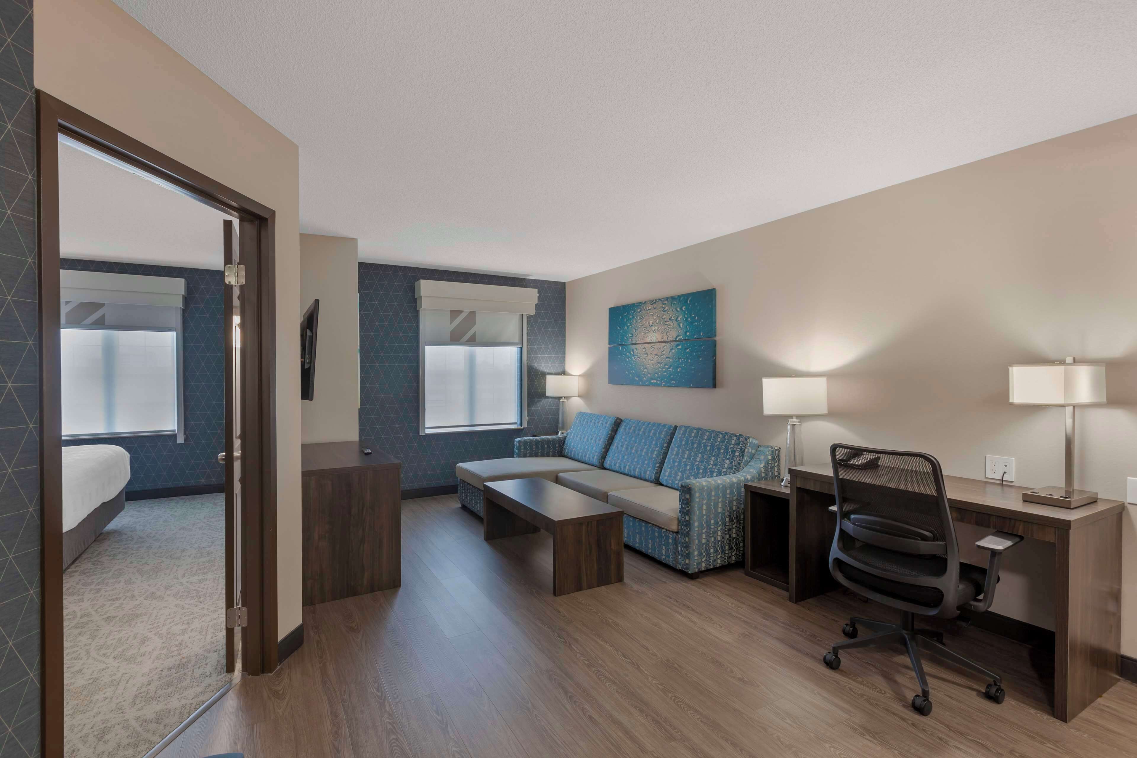 Quarto de hotel moderno com cama, sofá, escrivaninha e cadeira.