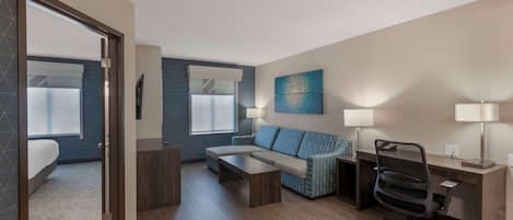 A modern hotel room with a bed, a sofa, a desk, and a chair.