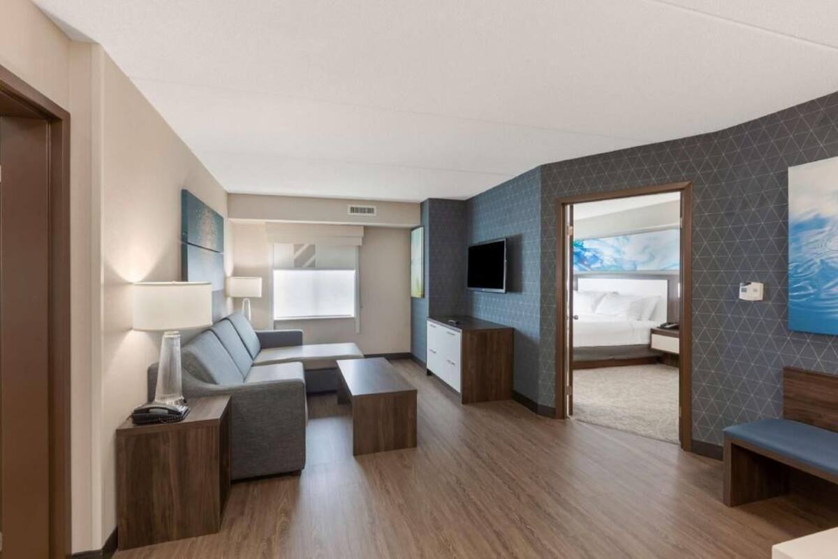 Een moderne hotelkamer met een bank, een televisie, een bureau en een bed.