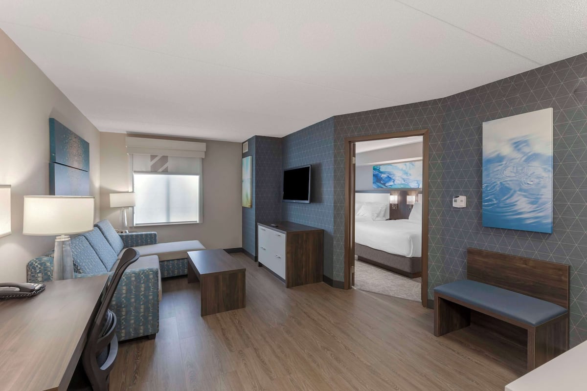 Una habitación de hotel moderna con comedor, sofá, televisor y cama.