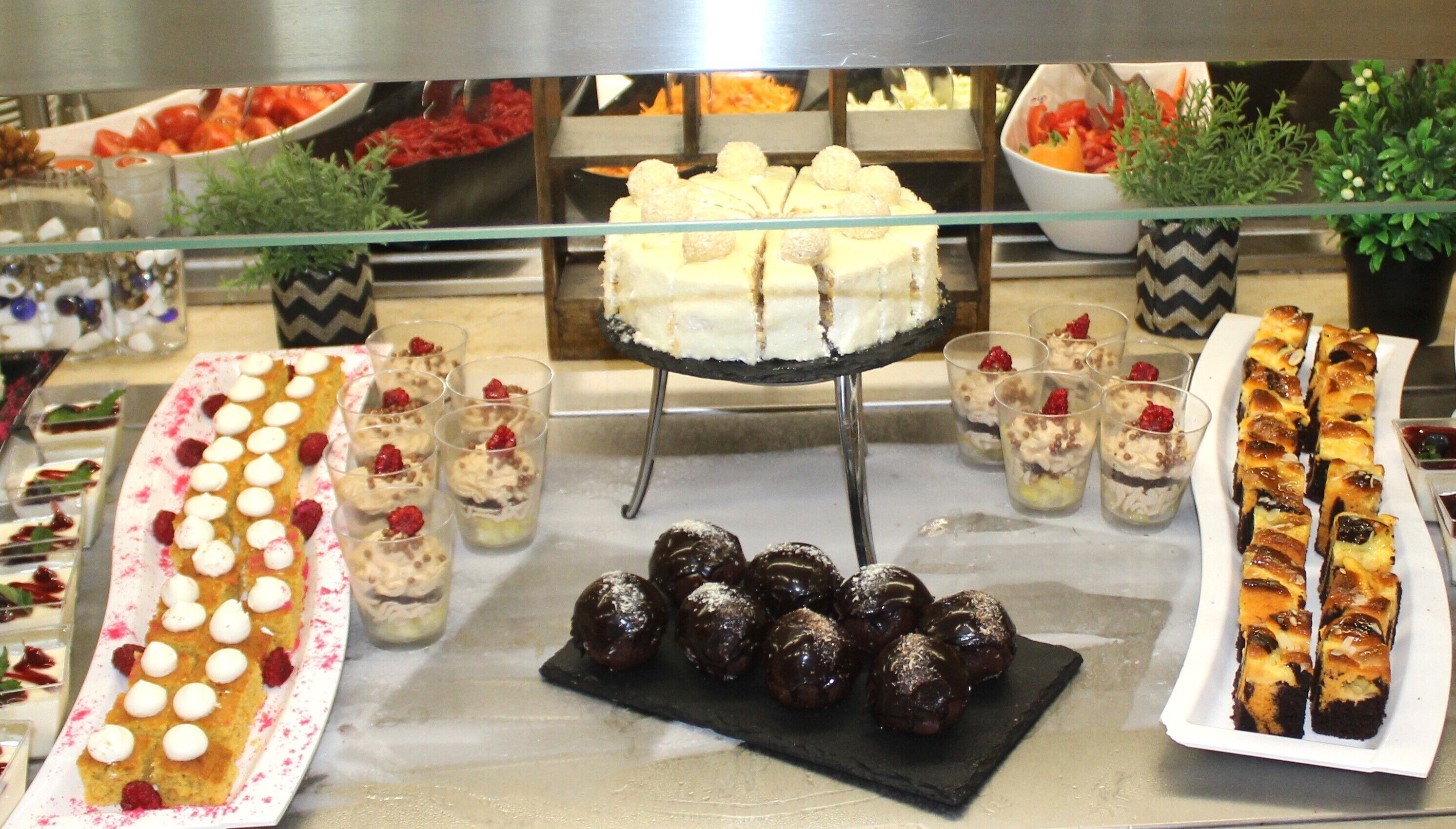 A buffet with various desserts including cakes, pastries, and fruit.