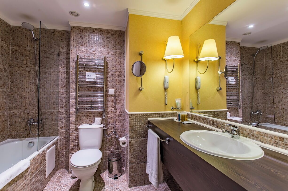A bathroom with a bathtub, toilet, sink, and a large mirror.