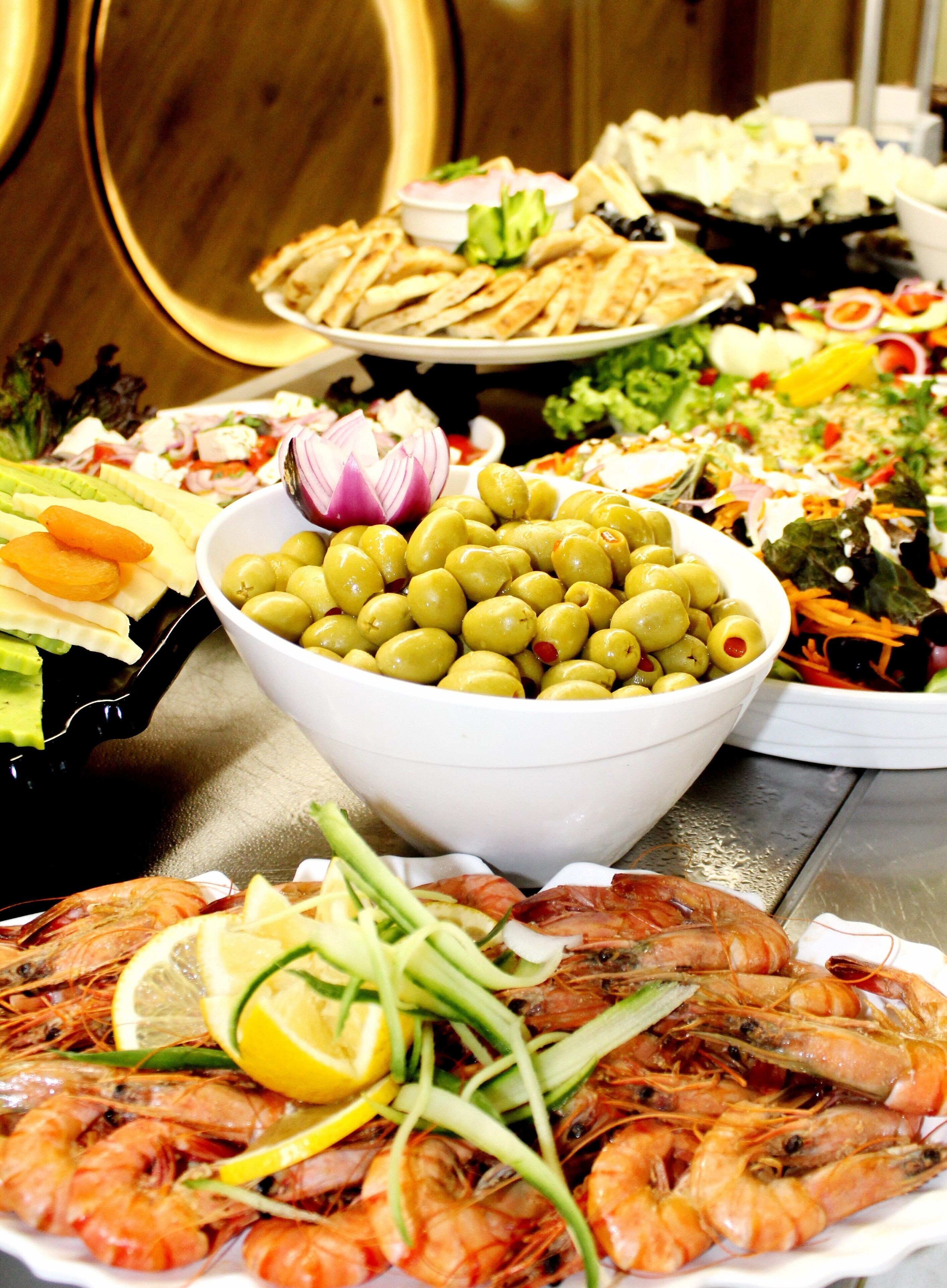 A table with various dishes including shrimp, olives, and salads.