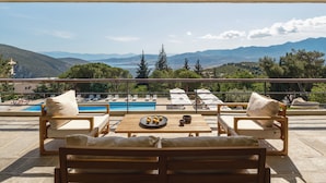 A terrace with wooden furniture, a table with lemons, and a view of mountains and a pool. - Amalia Hotel Delphi (Delphi)