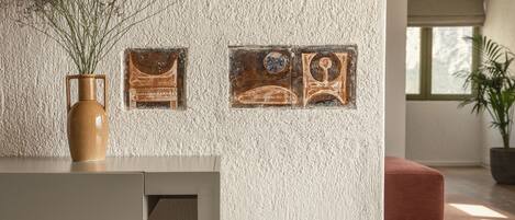 A modern interior with a textured wall, a vase with dried flowers, and two framed artworks.