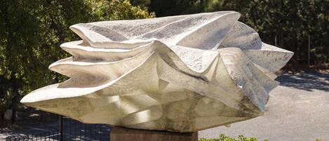 A stone sculpture in a park with a view of mountains and a lake.