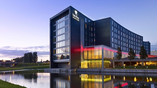 A modern hotel with a prominent 'Park Plaza' sign, large windows, and a reflection in a water body. - Park Plaza Amsterdam Airport (Lijnden)