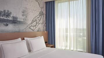 Een hotelkamer met een groot bed, een hoofdeinde, een nachtkastje en een wereldkaart aan de muur.