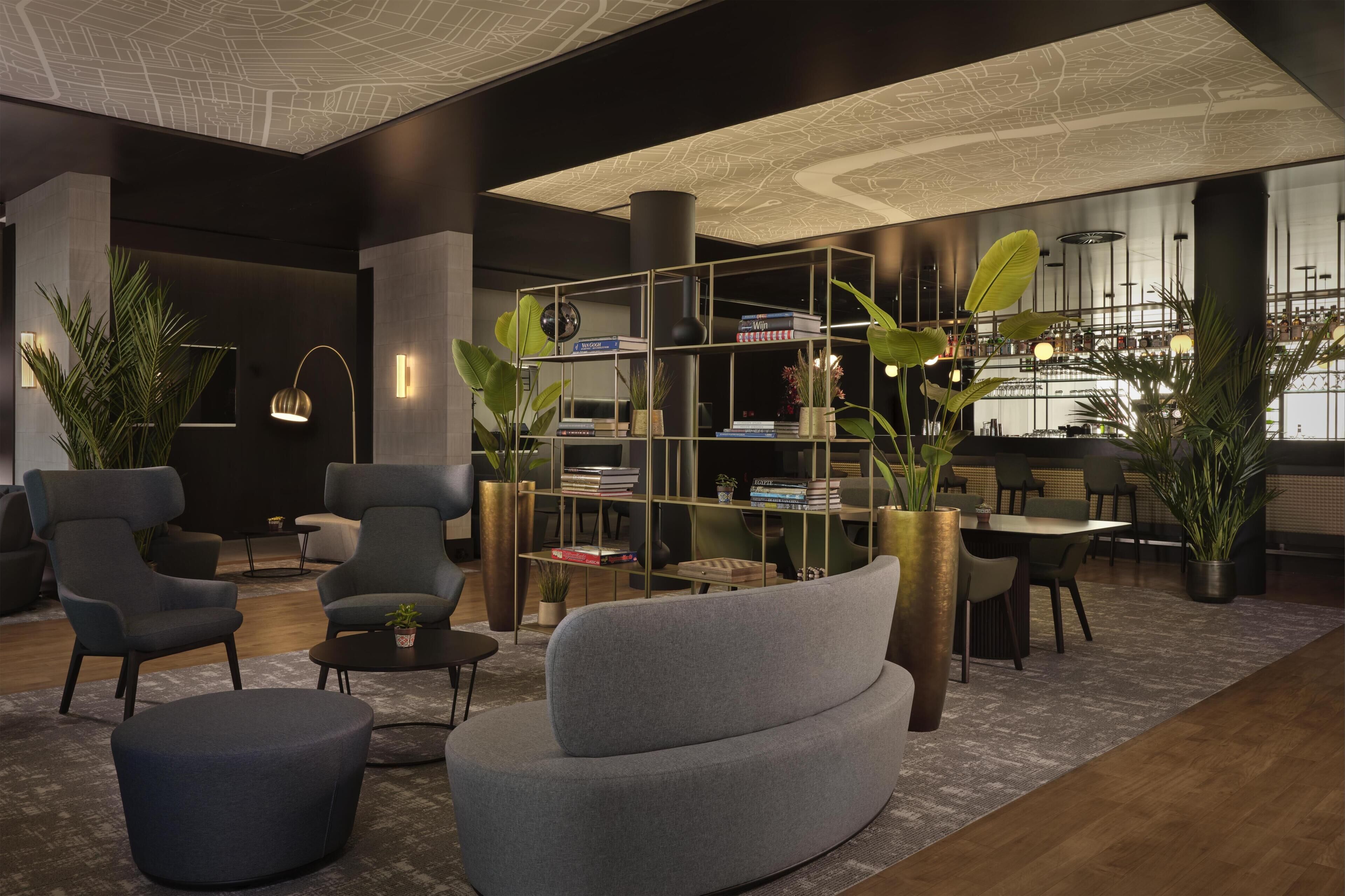 Een moderne lounge met zitplaatsen, een boekenkast en een bar op de achtergrond.