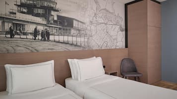 Quarto de hotel com duas camas, um mapa na parede e um guarda-roupa de madeira.