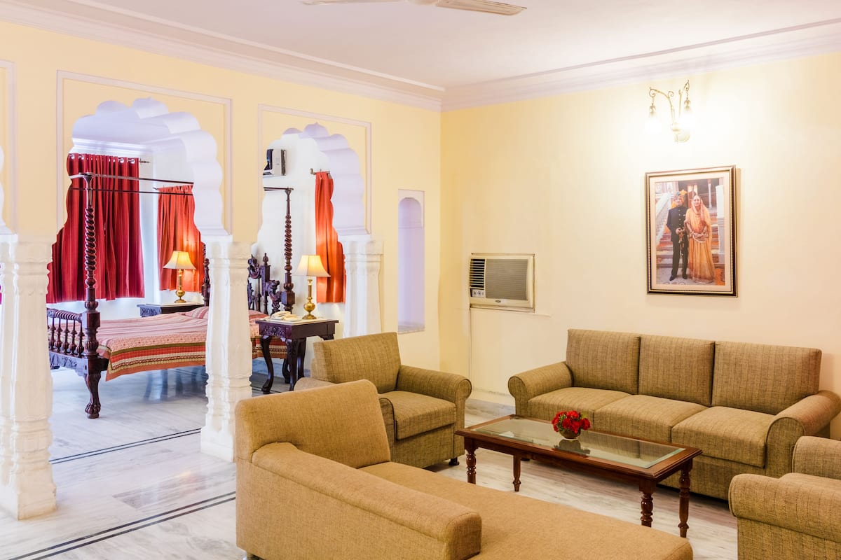 Ein traditionell eingerichteter Raum mit Bett, Sofas, einem Couchtisch und Deckenventilator.