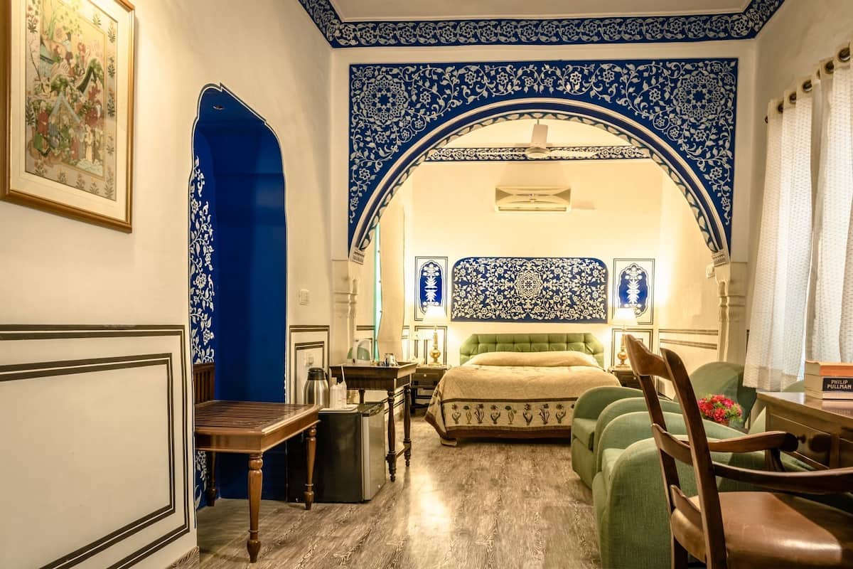 Ein Zimmer mit einem Bett, einem Schreibtisch, einem Stuhl, einem Tisch und einer blauen Tür.