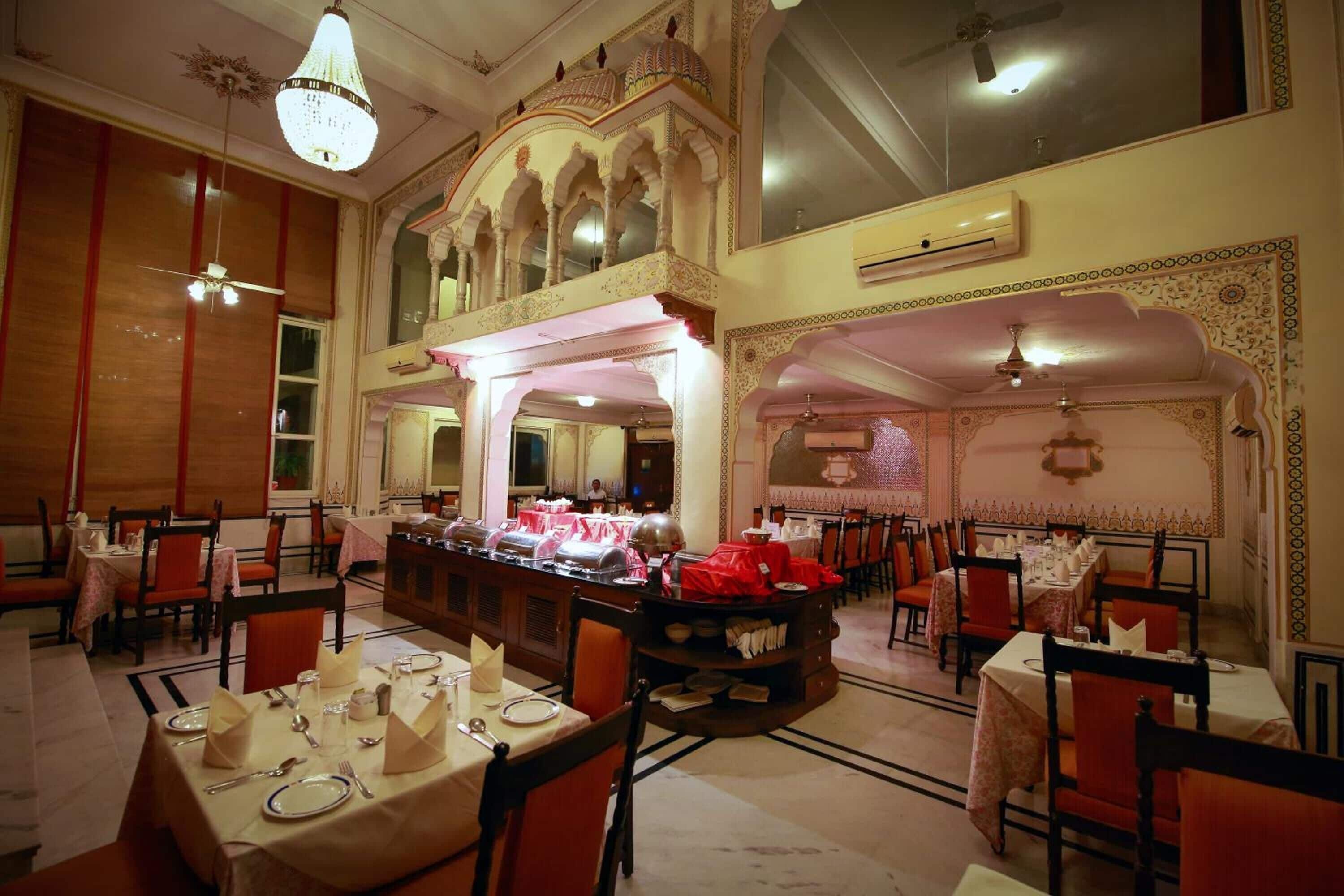 A restaurant with multiple dining tables, some covered with tablecloths, and chairs arranged around them.
