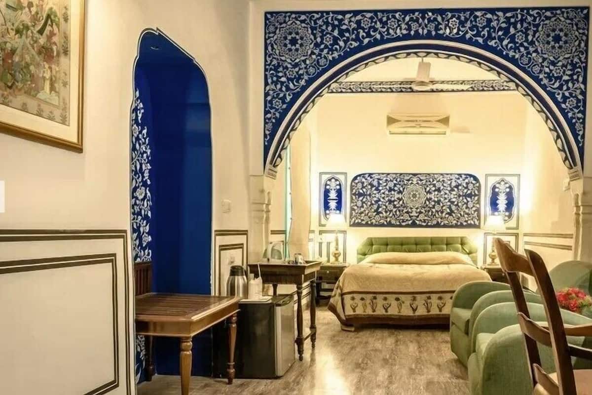 A room with a bed, a desk, a chair, and a decorative archway.
