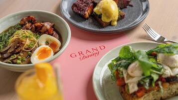 Una mesa con tres platos de comida, un tenedor y un menú que dice 'GRAND Dining'.