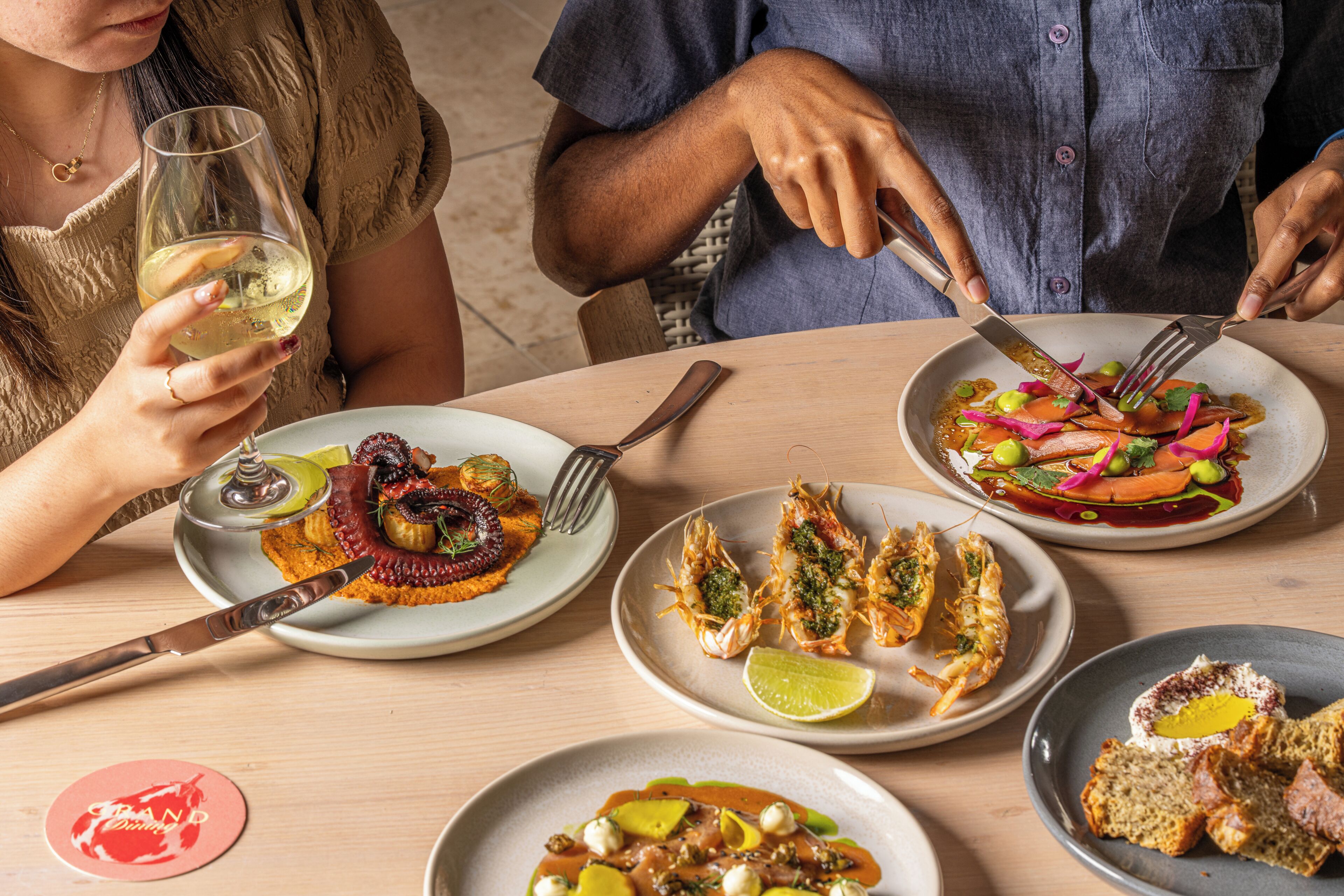 A dining table with various dishes, utensils, and a wine glass.