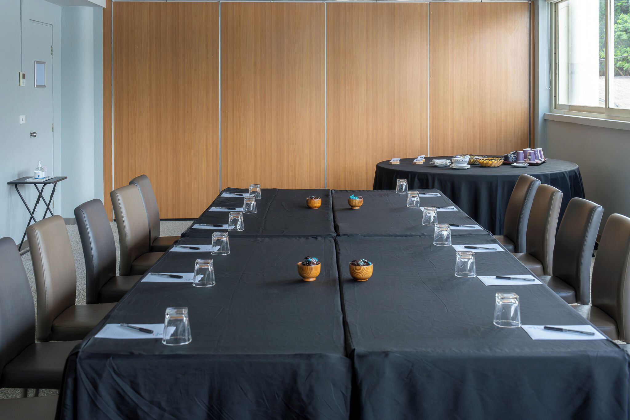 A conference room with a long table, chairs, and a wooden partition wall.