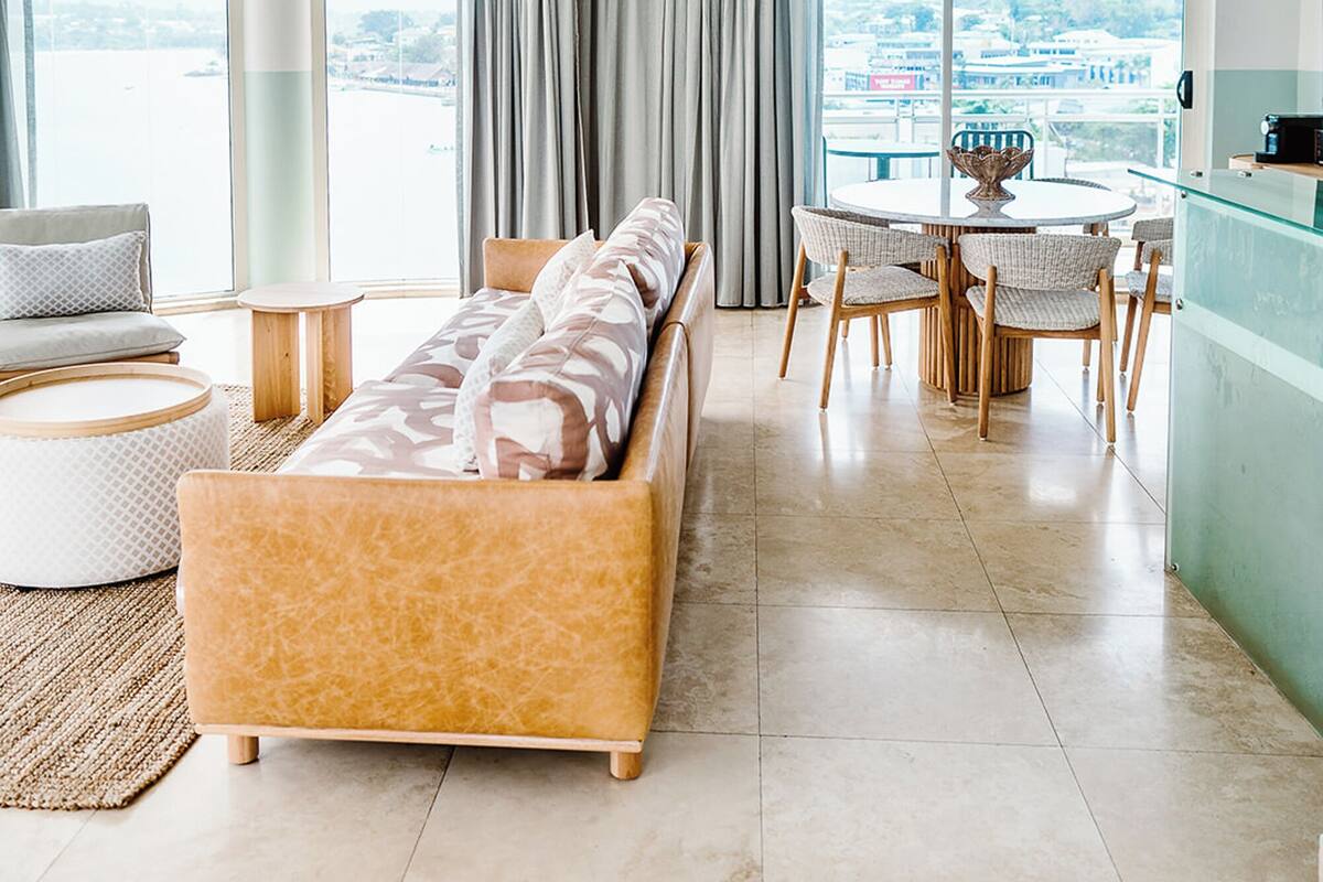 A modern living room with a sofa, chairs, a dining table, and a view of the water.