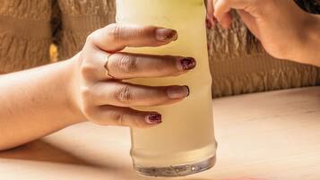 A person holding a tall glass with a straw, a lime wedge, and ice cubes.