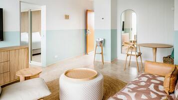 A modern hotel room with a sofa, ottoman, round table, and chairs.