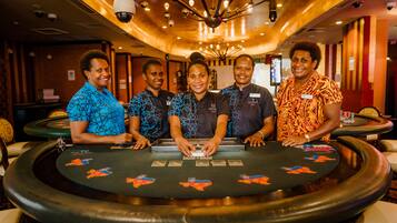 A group of five people standing behind a blackjack table in a casino setting.