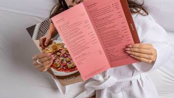 A person lying on a bed with a menu.
