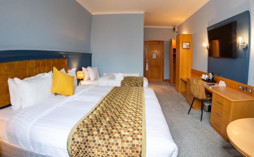 A hotel room with a large bed, a desk, a chair, a television, and a bathroom.