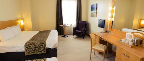 A hotel room with two beds, a desk, a chair, a television, and a large mirror.