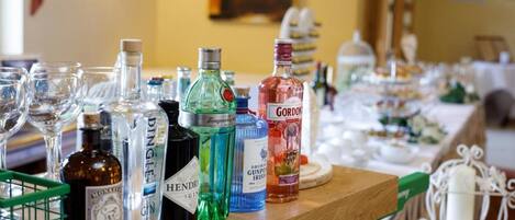 Una zona de bar con varias botellas de licores y vasos sobre una barra de madera.