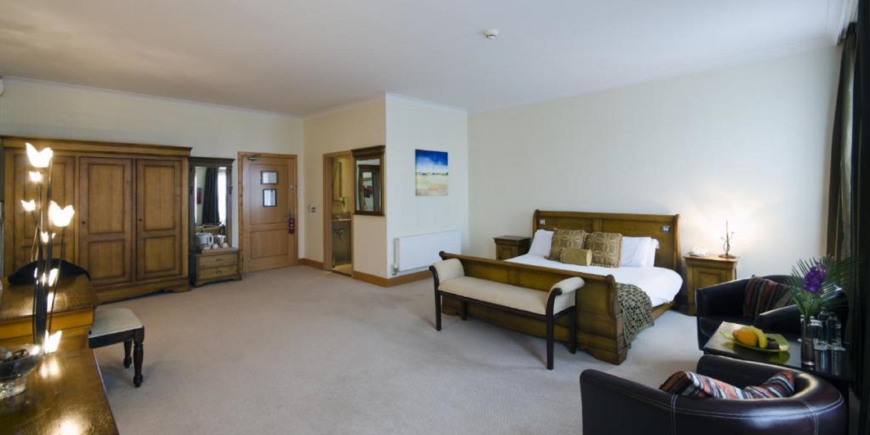 A bedroom with a bed, a bench, a desk, and a wardrobe.