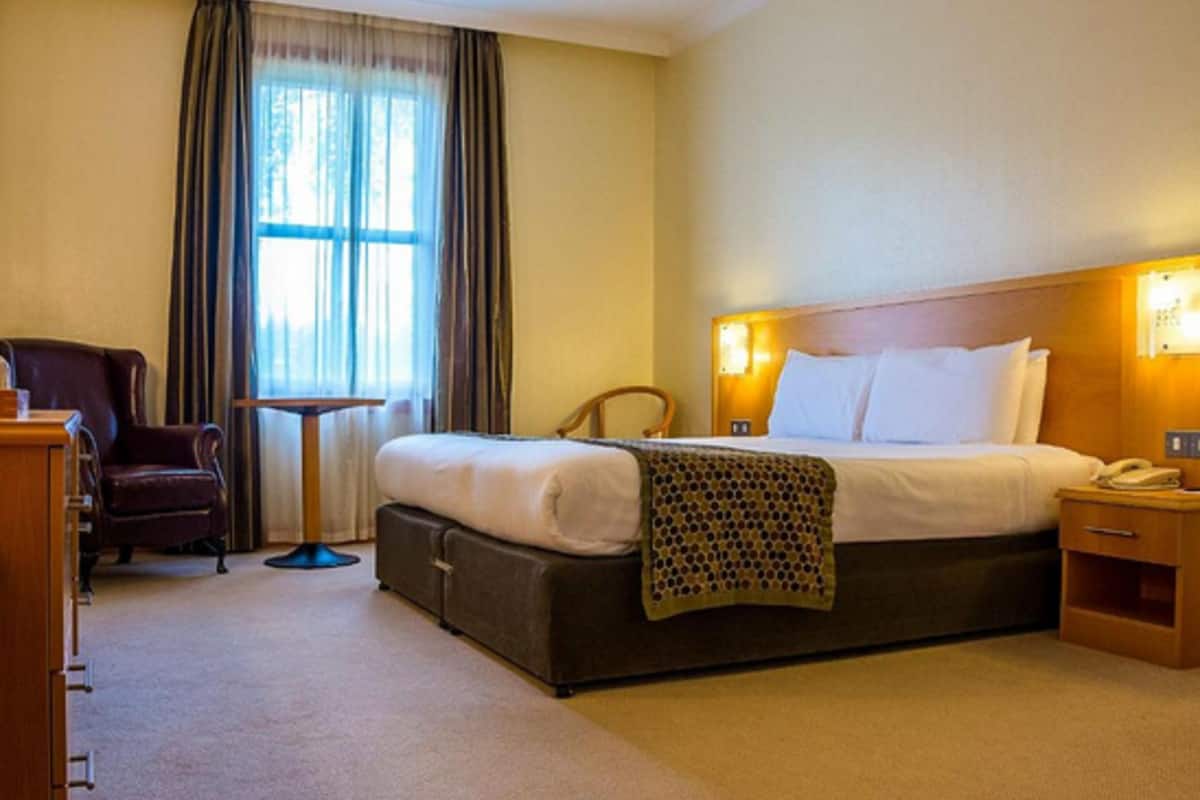 Een hotelkamer met een bed, een stoel, een bureau en een raam met gordijnen.