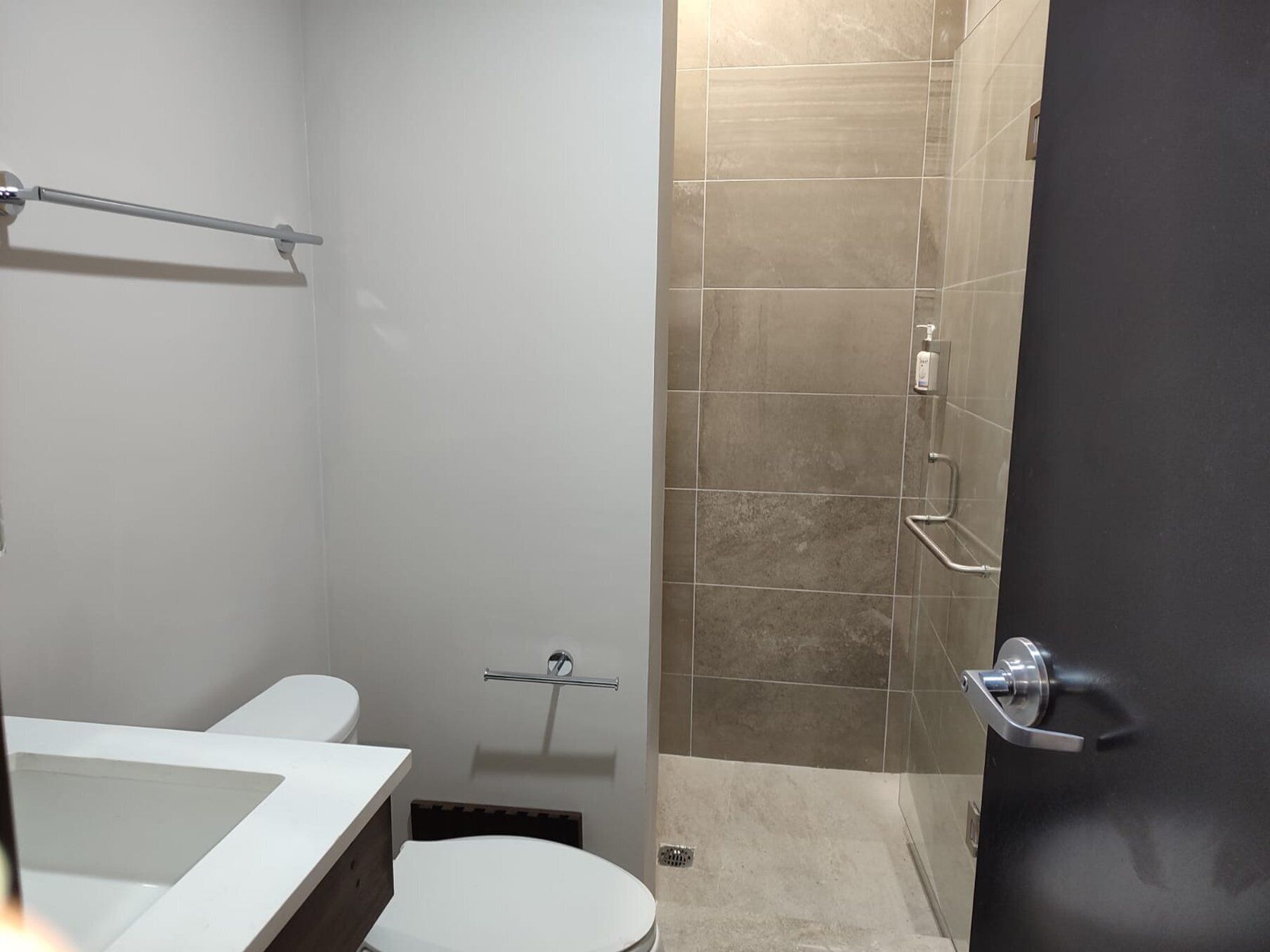 A modern bathroom with a white sink, toilet, and shower area.