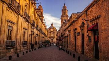 A historic street with buildings on either side, a central dome, and a bell tower.