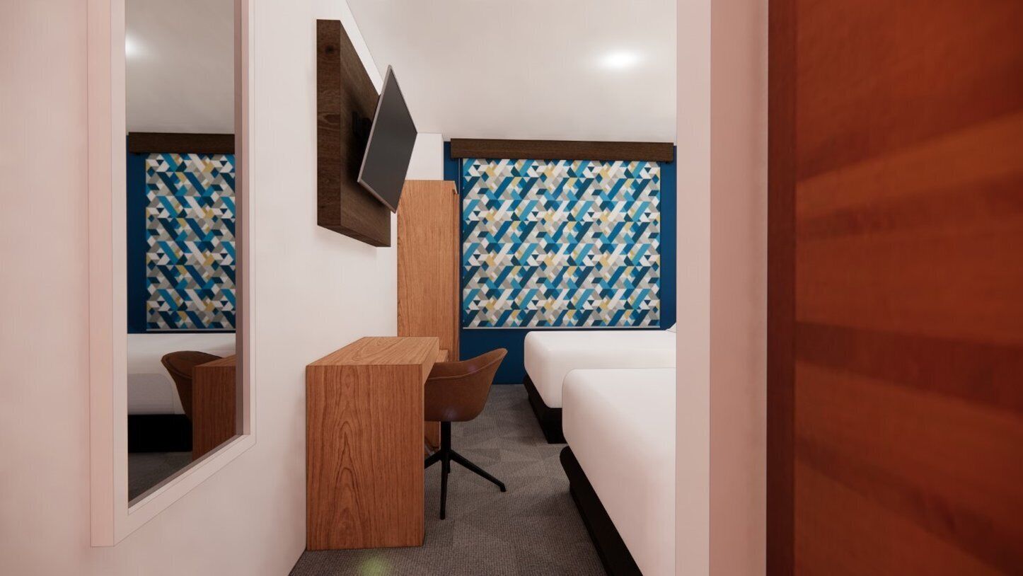 A modern hotel room with a desk, chair, and a bed.